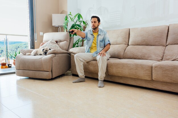 handsome Hispanic man sitting on a sofa and watching TV