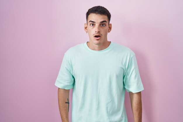 Handsome hispanic man standing over pink background afraid and shocked with surprise and amazed expression fear and excited face
