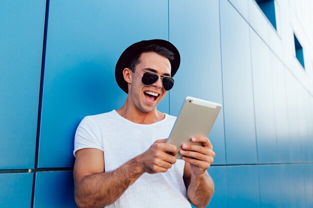 Handsome joyful man looking at tablet screen, laughing cheerfully, watching something.