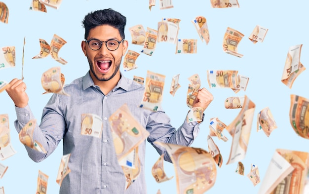 Free photo handsome latin american young man wearing business clothes and glasses screaming proud celebrating victory and success very excited with raised arms