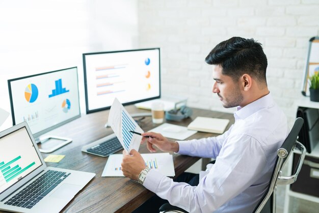 Handsome Latin businessman examining sales data while working at home