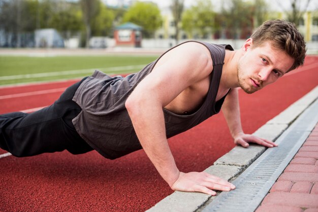 Handsome male athlete doing pushup on race track