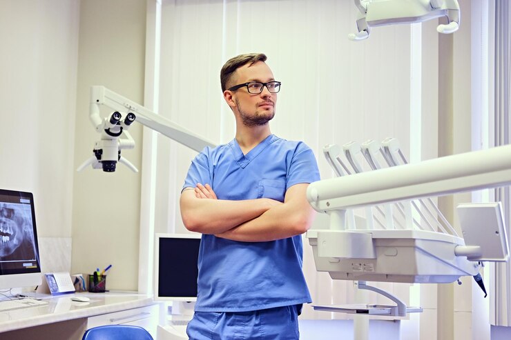 Free Photo handsome male dentist in a room with medical equipment on background.