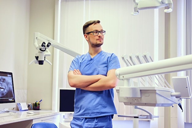 Handsome male dentist in a room with medical equipment on background.