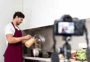 Free photo handsome male recording cooking video at home