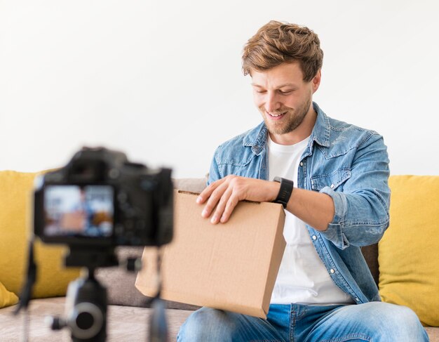 Handsome male recording while unboxing product