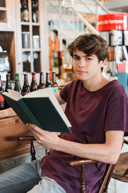Handsome male teenager with book looking at camera
