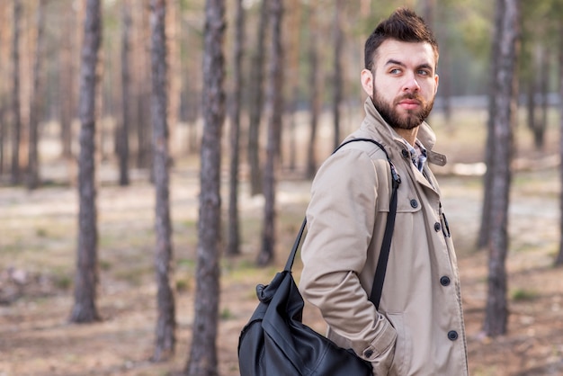 Free photo handsome male traveler with backpack on his shoulder looking away