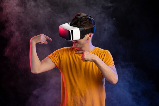 Handsome male wearing virtual reality headset on dark surface