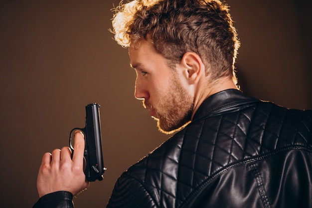 Free photo handsome man actor posing in studio with weapon