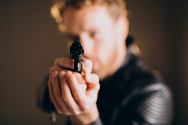 Free photo handsome man actor posing in studio with weapon