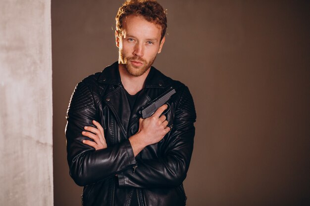 Handsome man actor posing in studio with weapon