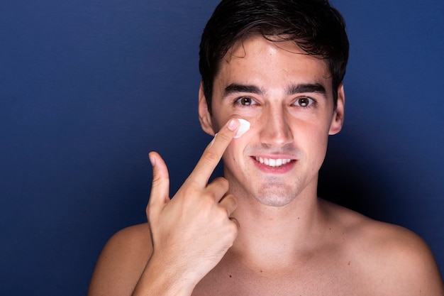 Handsome man applying skin care treatment