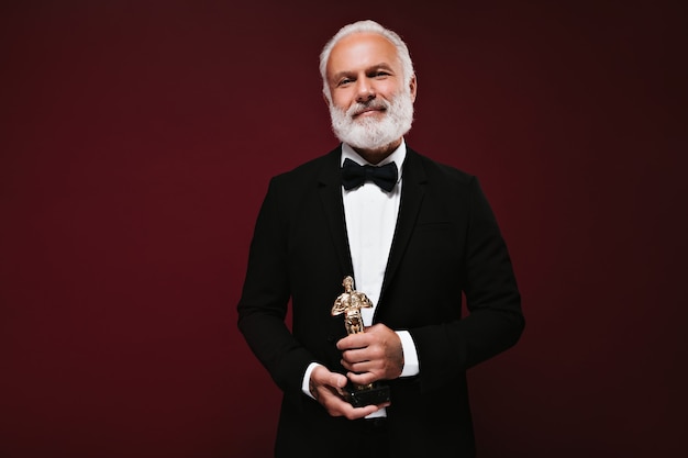 Handsome man in black jacket holding Oscar statuette