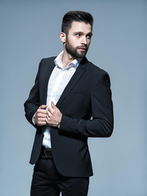 Handsome man in black suit with white shirt  - posing   Attractive guy with fashion hairstyle.  Confident man with short beard. Adult boy with brown hair. Full portrait.