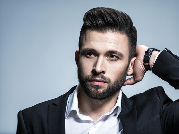Handsome man in black suit with white shirt  - posing   Attractive guy with fashion hairstyle.  Confident man with short beard. Adult boy with brown hair.