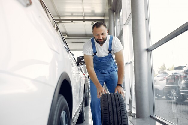 青い制服を着たハンサムな男が車をチェックします