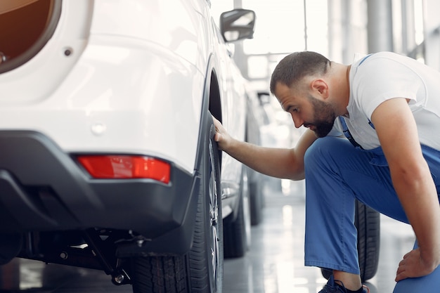 青い制服を着たハンサムな男が車をチェックします