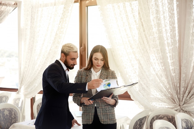 Free photo handsome man and a brunette woman are looking at the diagramme, being in the light room