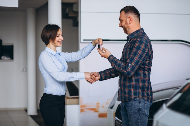 Foto gratuita uomo bello che compra un'automobile in una sala d'esposizione dell'automobile