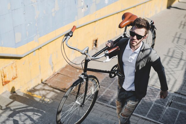 Handsome man carrying bicycle walking on staircase