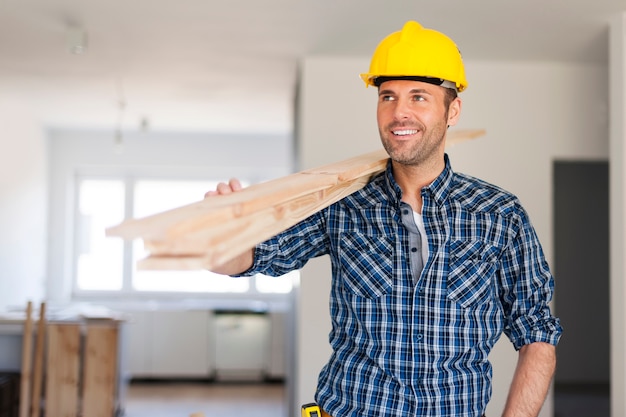 Handsome man carrying wood planks