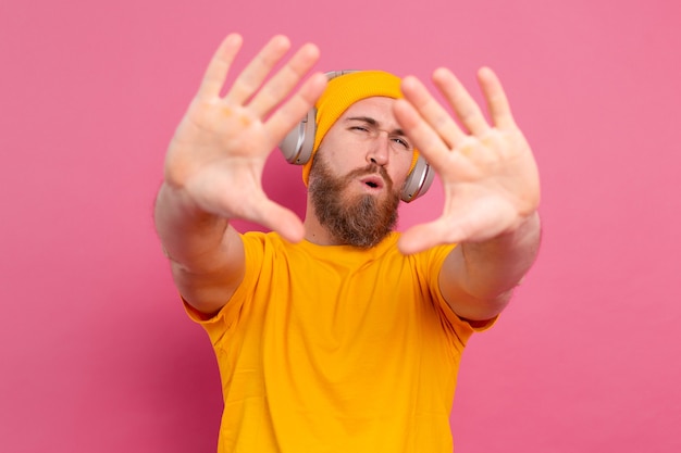 Uomo bello in ascolto casuale di musica con le cuffie isolato su sfondo rosa