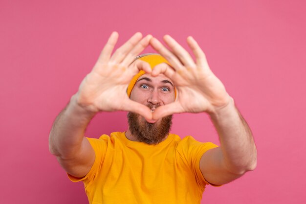 Handsome man in casual listening to music with headphones isolated on pink background