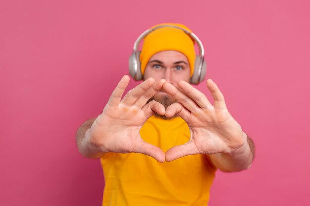 Foto gratuita uomo bello in ascolto casuale di musica con le cuffie isolato su sfondo rosa