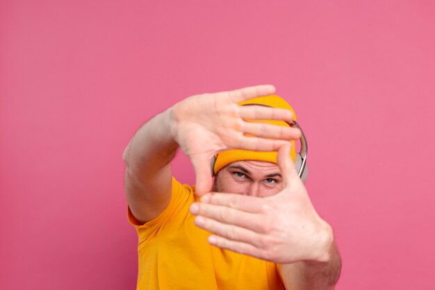 Handsome man in casual listening to music with headphones isolated on pink background