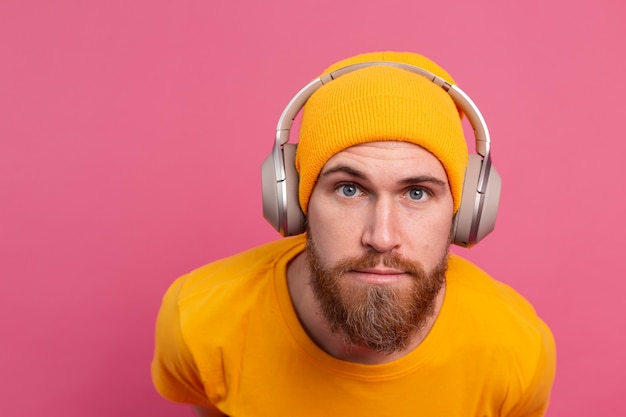 Foto gratuita uomo bello in ascolto casuale di musica con le cuffie isolato su sfondo rosa