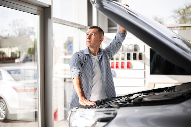 Foto gratuita uomo bello che controlla un'automobile al concessionario