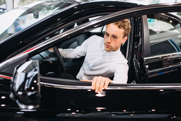 Foto gratuita uomo bello che sceglie un'automobile in una stanza di manifestazione