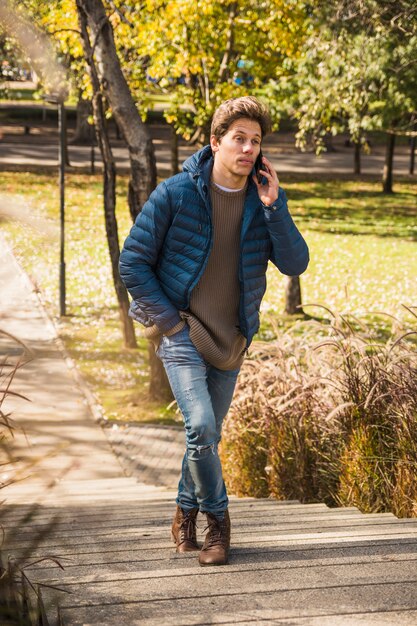 Handsome man climbing staircase while talking on smart phone