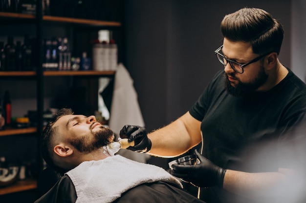 Handsome man cutting beard at a barber salon