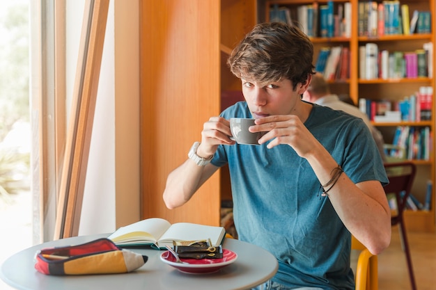 Handsome man drinking coffee in reading hall