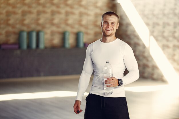 Free photo handsome man drinking water at the gym