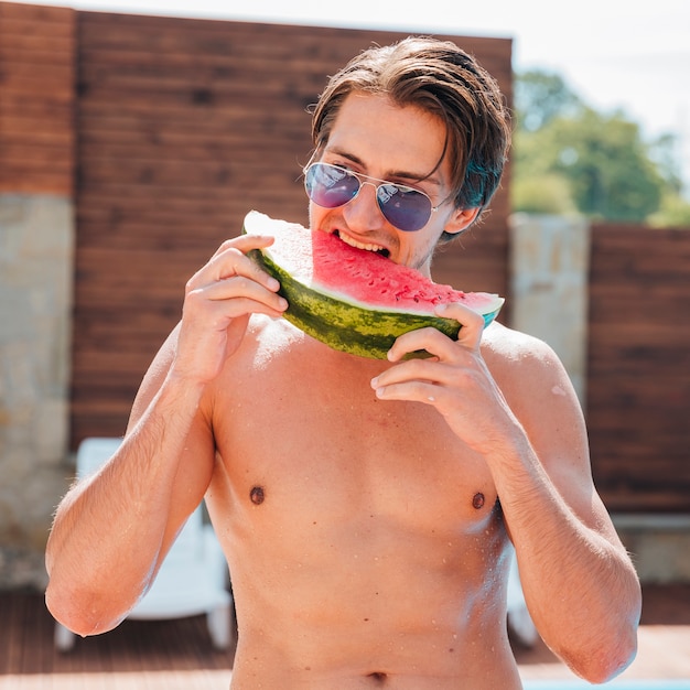 Handsome man eating watermelon