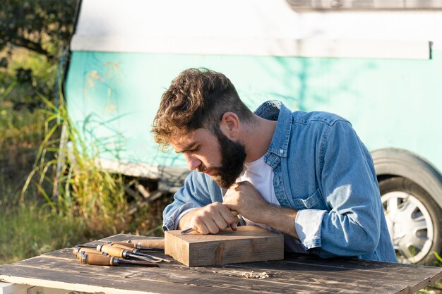 Handsome man engraving in wood outdoors