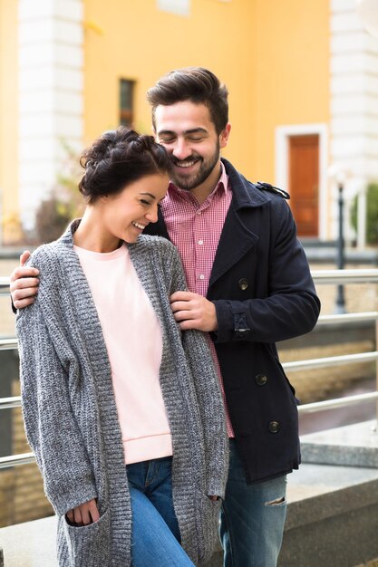 Handsome man enjoying daytime with his girl Happy couple hugging on the street during autumn weather