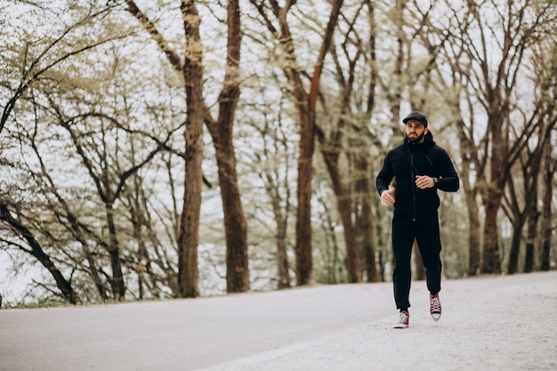 Uomo bello che si esercita nel parco nell'usura di sport