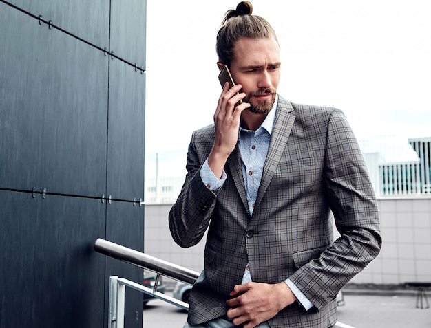 Handsome man in gray checkered suit speaking with smartphone