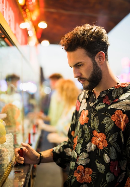 Foto gratuita uomo bello che mangia uno spuntino al luna park