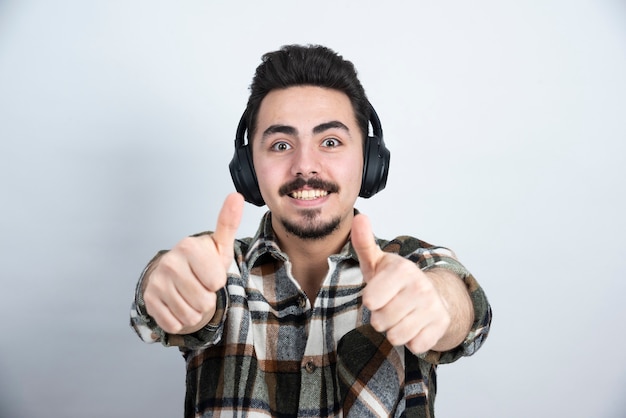 Free photo handsome man in headphones looking on white wall.