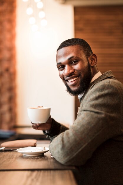 Handsome man holding a cup with coffee in a pub
