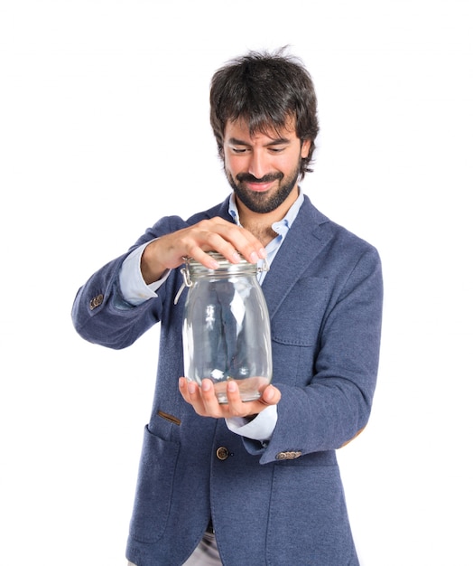 Handsome man holding an empty glass jar over isolated background