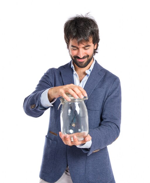 Handsome man holding an empty glass jar over isolated background