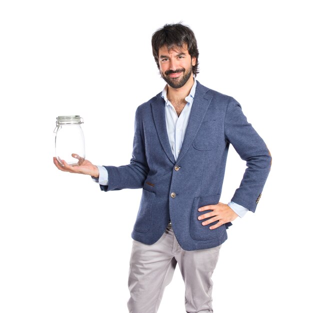 Handsome man holding an empty glass jar over isolated background