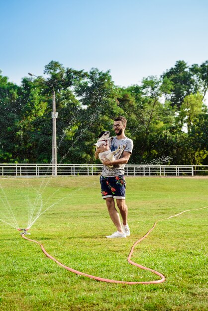 公園を歩いて、フレンチブルドッグを保持しているハンサムな男