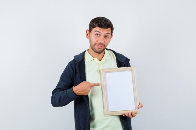 Handsome man holding a photo frame in a casual outfit